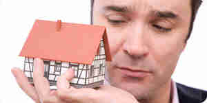 Homme tenant un modele miniature de la maison